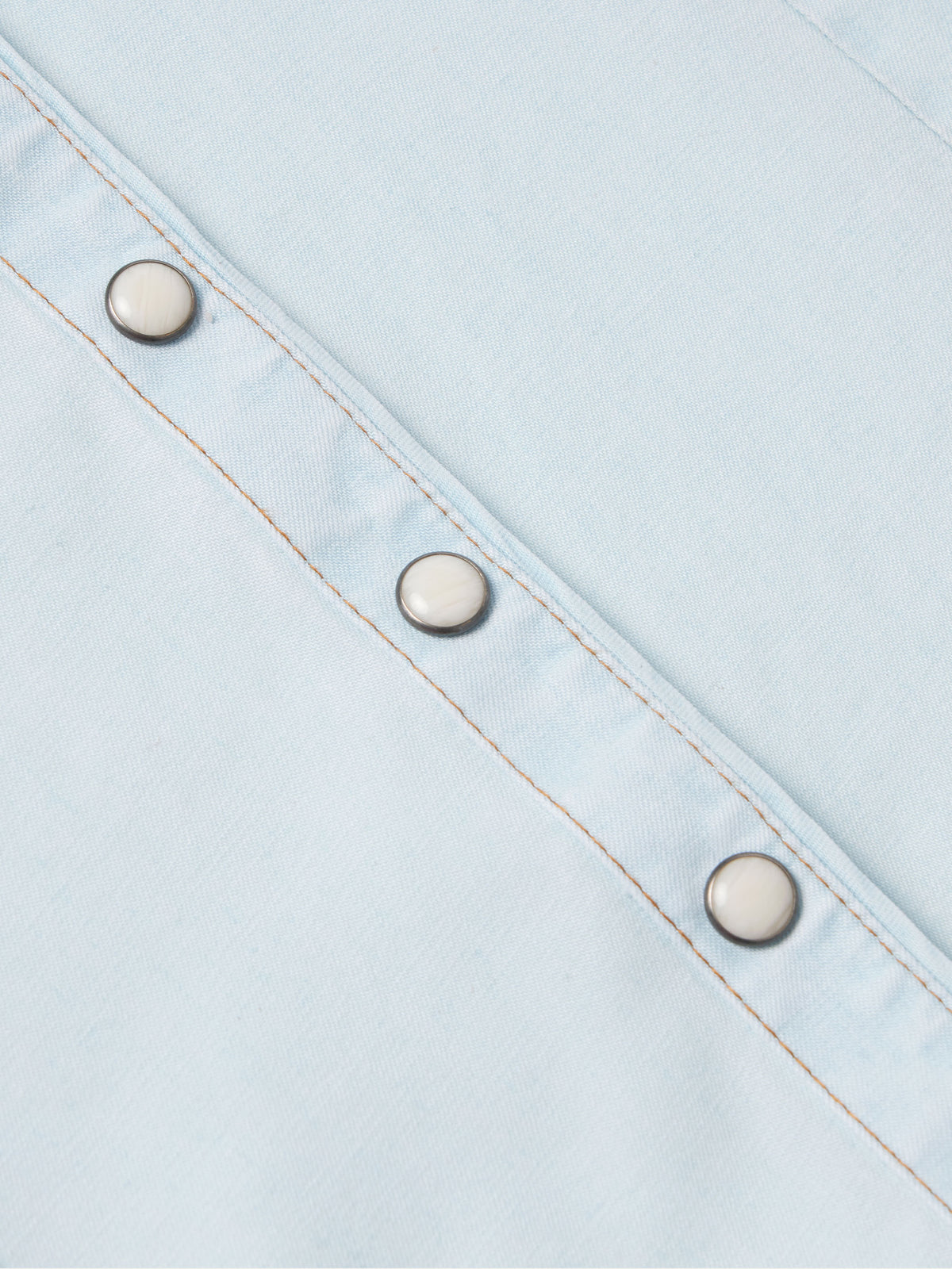 Light wash denim snap shirt sleeve placket with three metal snaps and orange stitching
