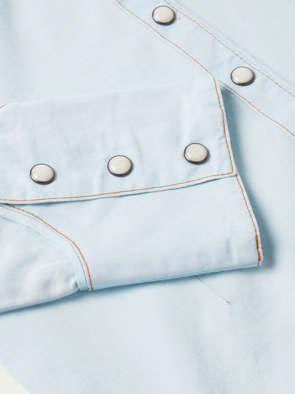 Light wash denim snap shirt chest pocket with metal snaps and curved yoke seam