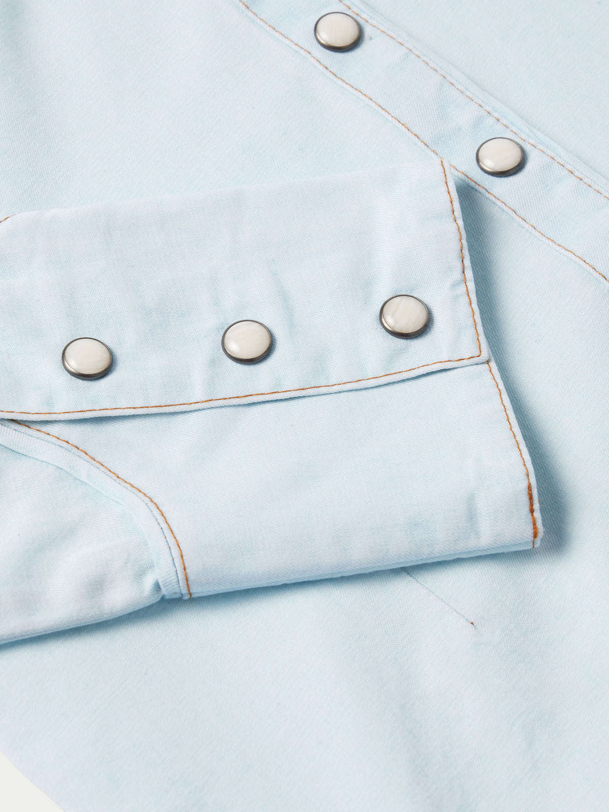 Light wash denim snap shirt chest pocket with metal snaps and curved yoke seam