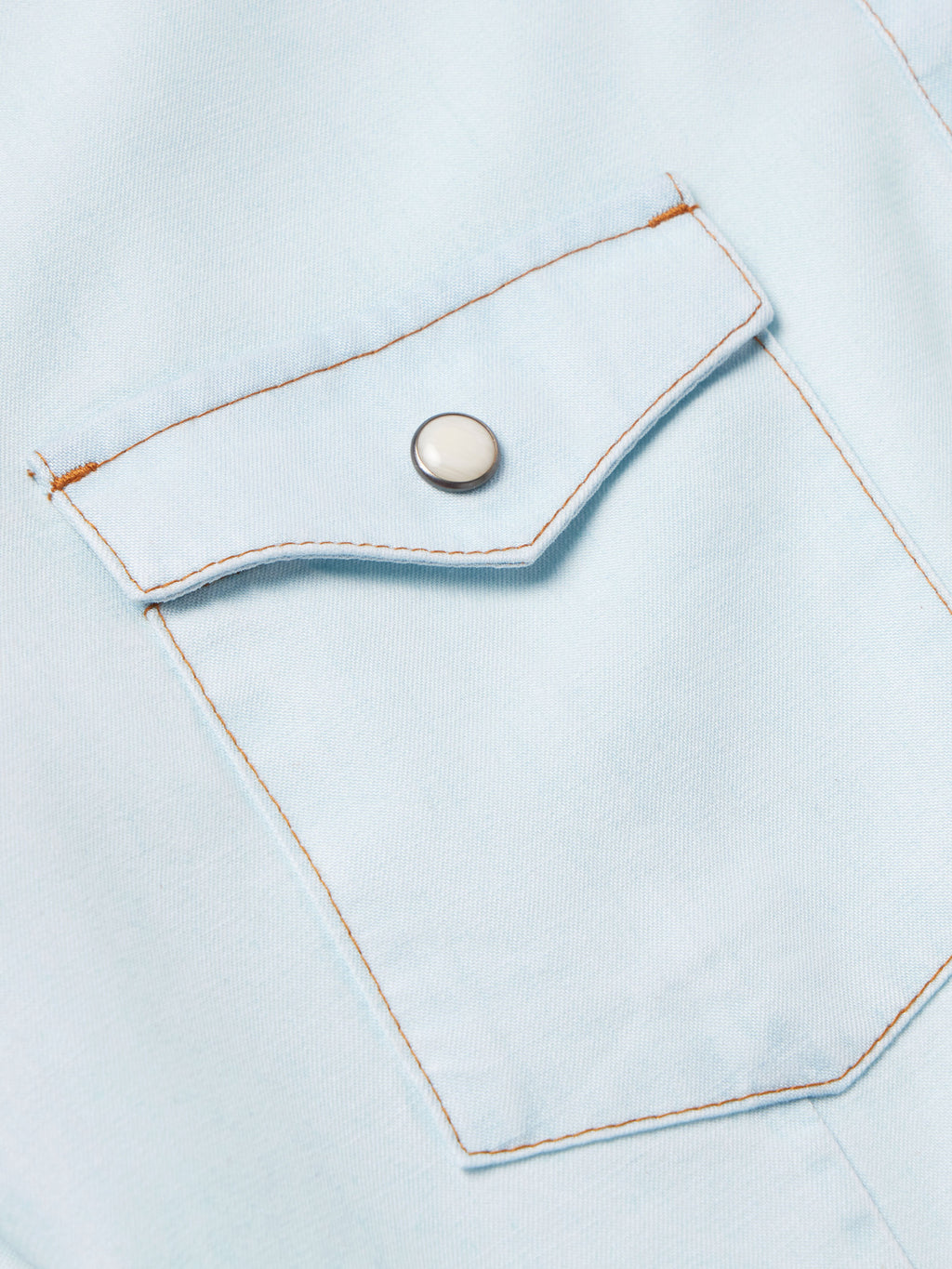 Light wash denim snap shirt placket with metal snap button and stitched pocket flap