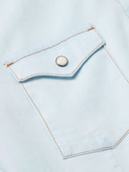 Light wash denim snap shirt placket with metal snap button and stitched pocket flap
