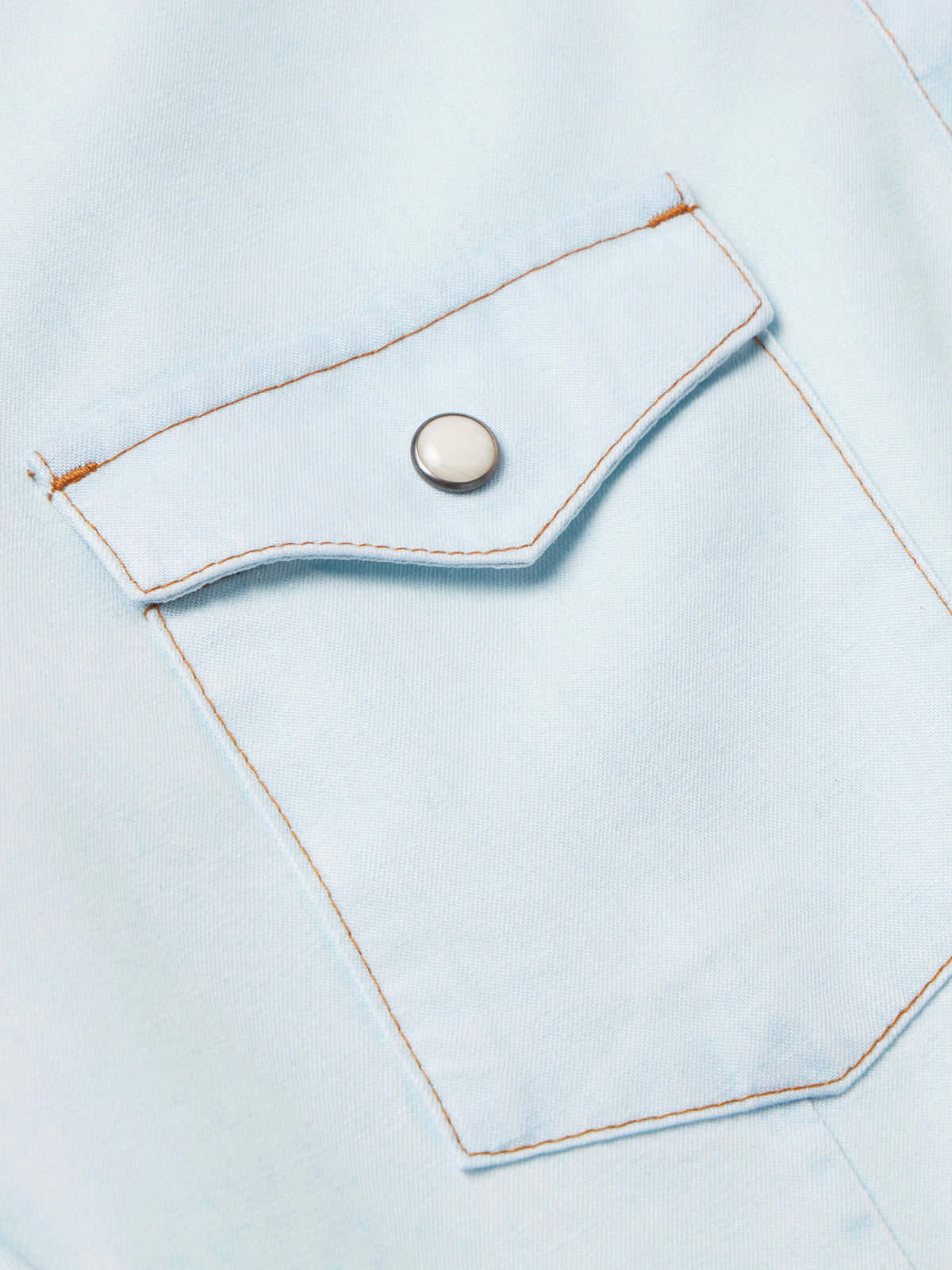 Light wash denim snap shirt placket with metal snap button and stitched pocket flap
