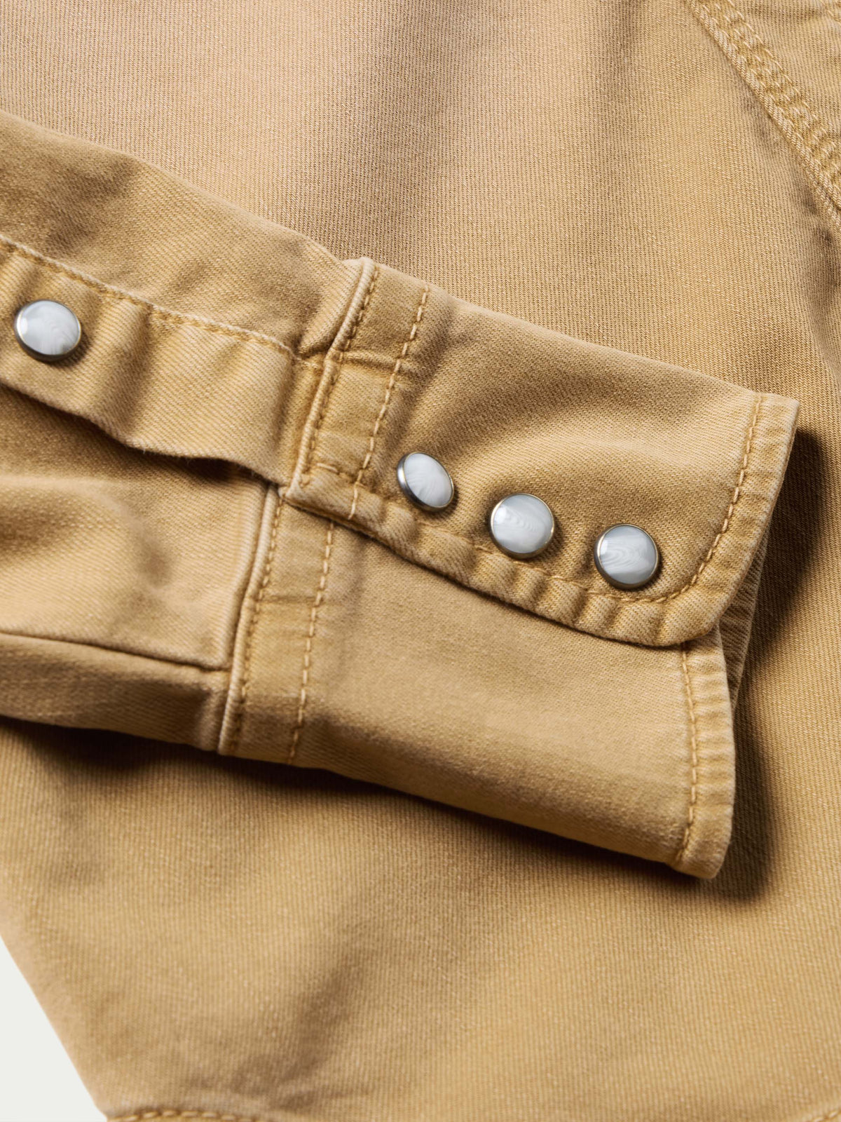 Faded chestnut denim snap shirt sleeve cuff with row of metal snap buttons
