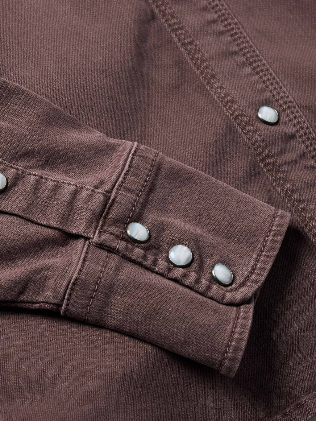 Faded maroon denim snap cuff detail with metal buttons