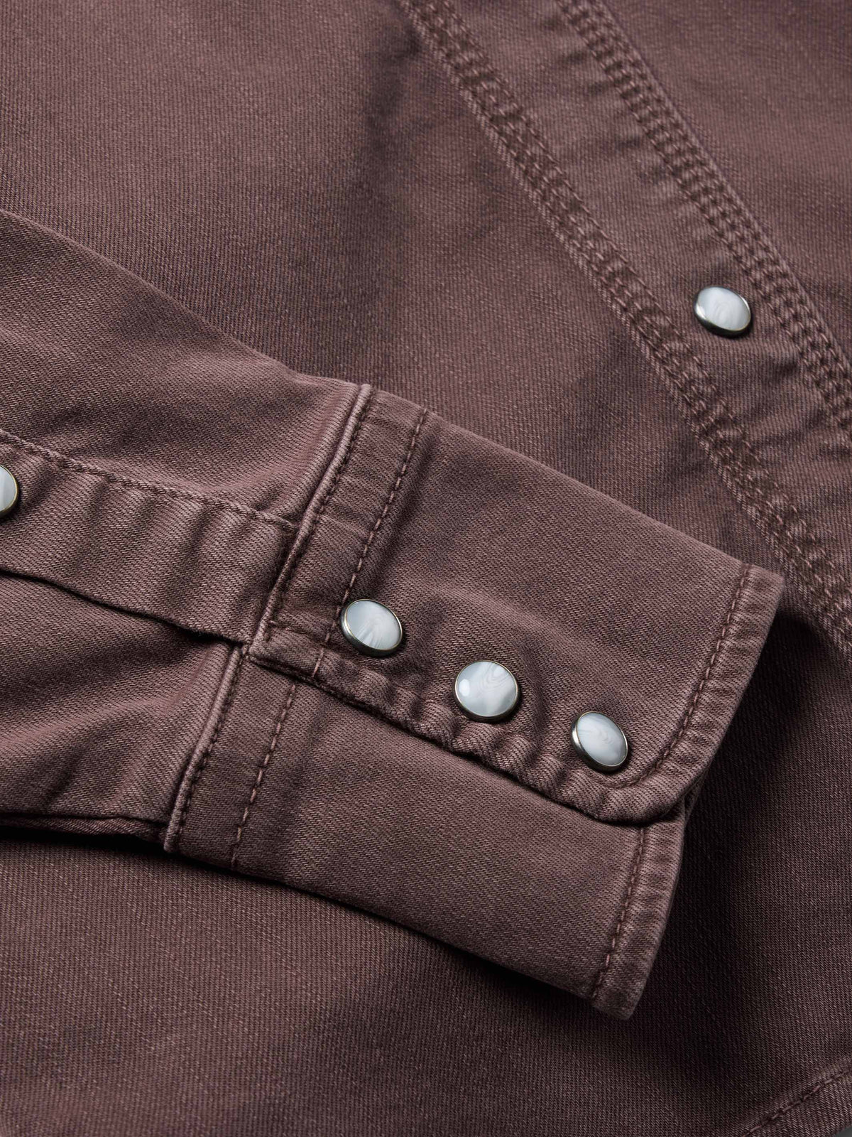 Faded maroon denim snap cuff detail with metal buttons