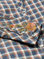 Women’s embroidered snap shirt close-up, blue plaid with floral embroidery and snap buttons