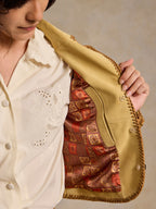 Buttercream suede jacket with open front revealing patterned lining and whipstitch trim