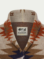Women's belted sweater with V-neck and label, cream knit with orange and blue pattern.