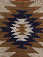 Women's belted sweater fabric close-up, cream knit with navy and rust star-like motif.