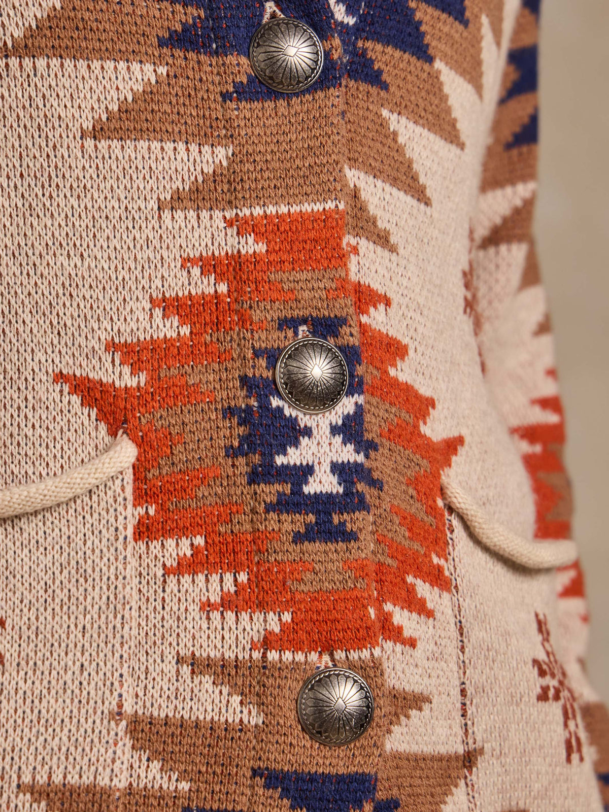 Women's belted sweater button detail, cream knit with navy and orange geometric motif.