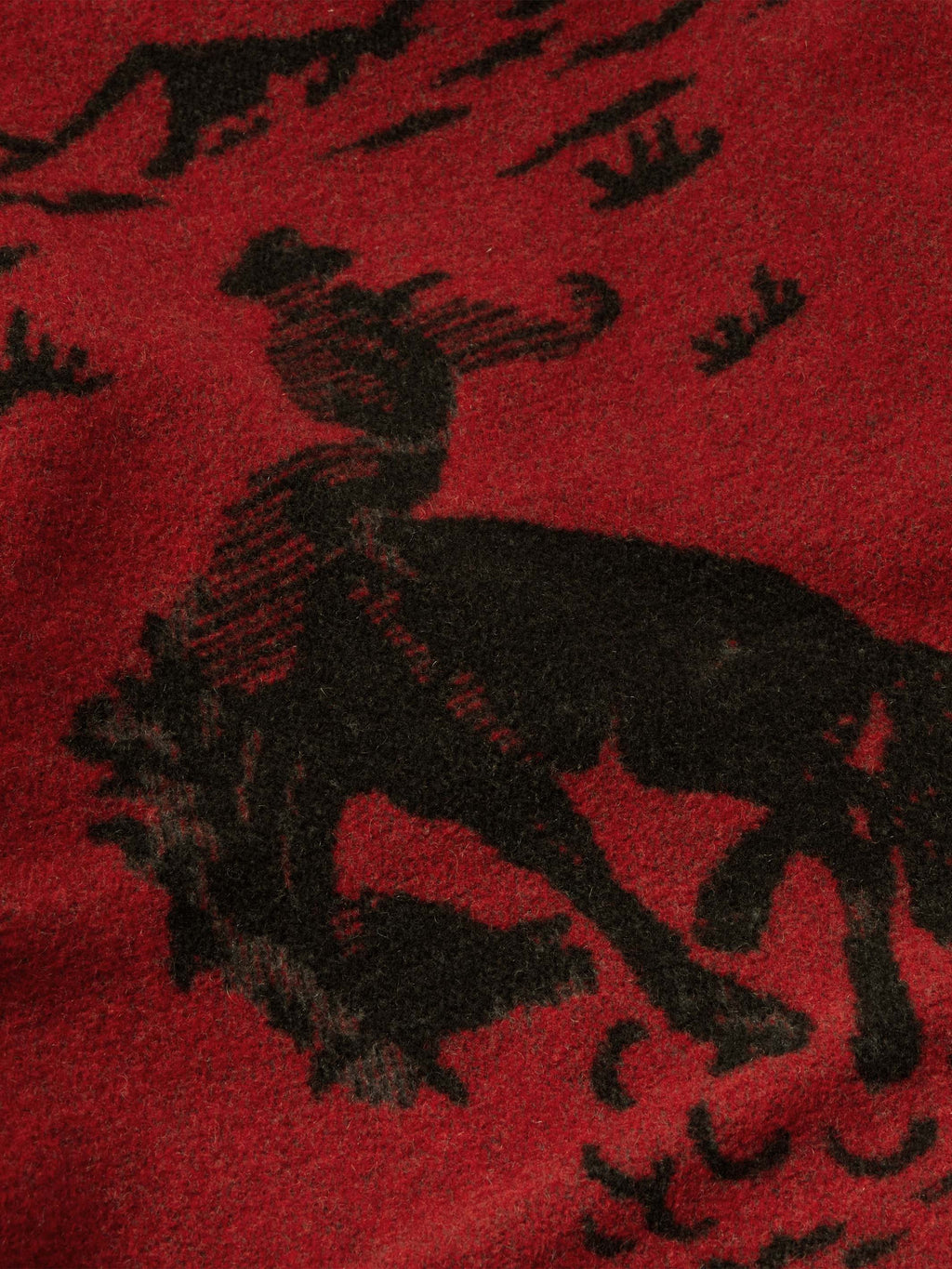 Crimson blanket-style coat with dark animal-inspired pattern and textured woven fabric