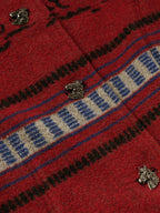 Crimson blanket-style coat with blue-and-cream striped trim and metal button details