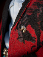 Close-up of crimson and dark gray blanket coat with ornate metal animal button