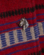 Crimson red blanket coat close-up with horse-head patch and blue-and-cream pattern.