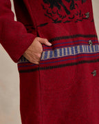 Crimson red blanket coat cuff detail with blue-striped band and small metal buttons.