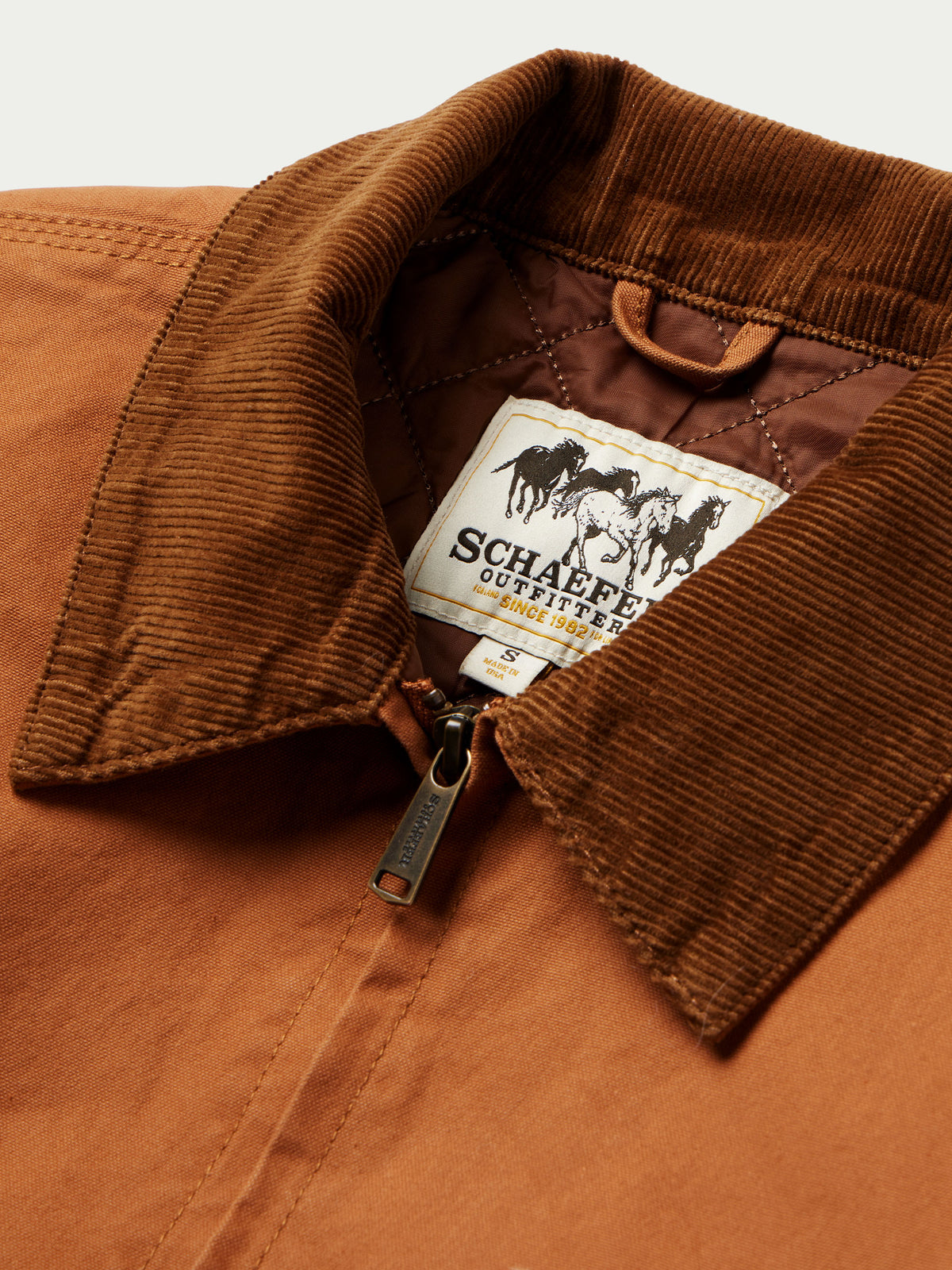 Close-up of rust-orange jacket interior label at corduroy-lined collar