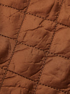 Close-up of rust-orange quilted lining with brown stitched grid pattern