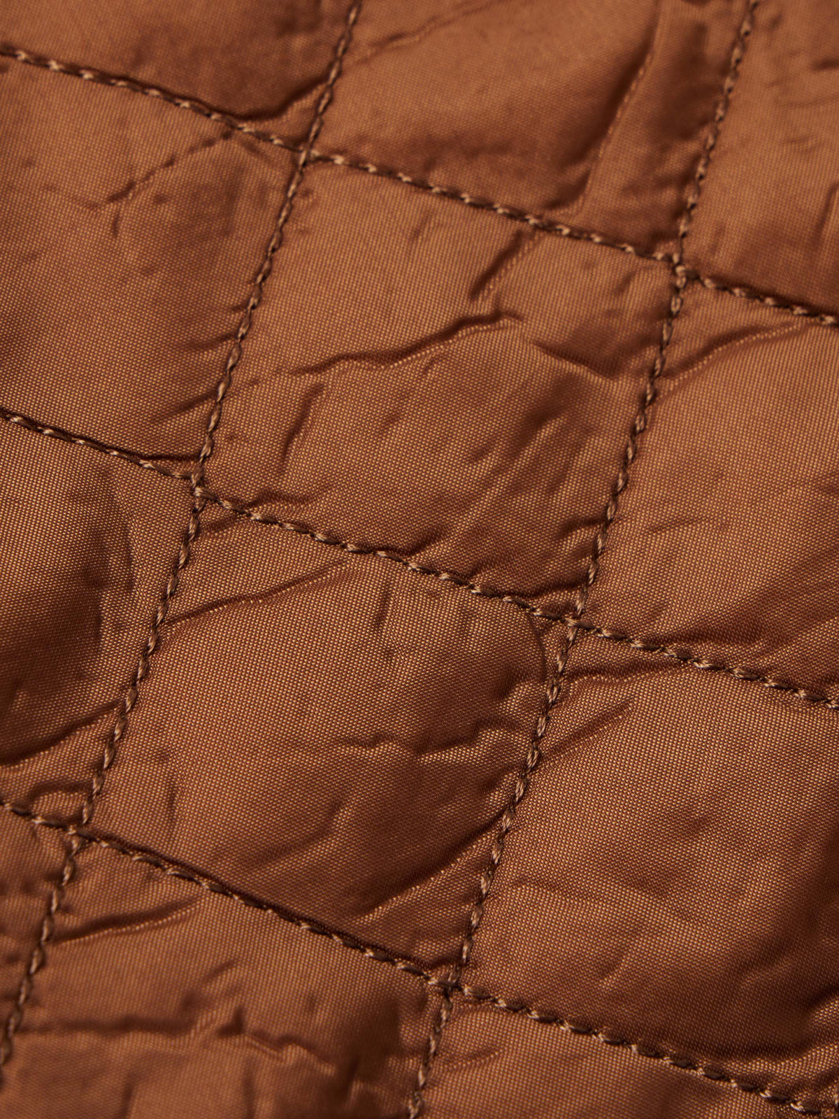 Close-up of rust-orange quilted lining with brown stitched grid pattern