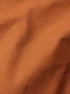 Close-up fabric texture of rust-orange cotton with visible woven grain