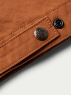 Close-up of rust-orange snap button and decorative embossed shank on hem