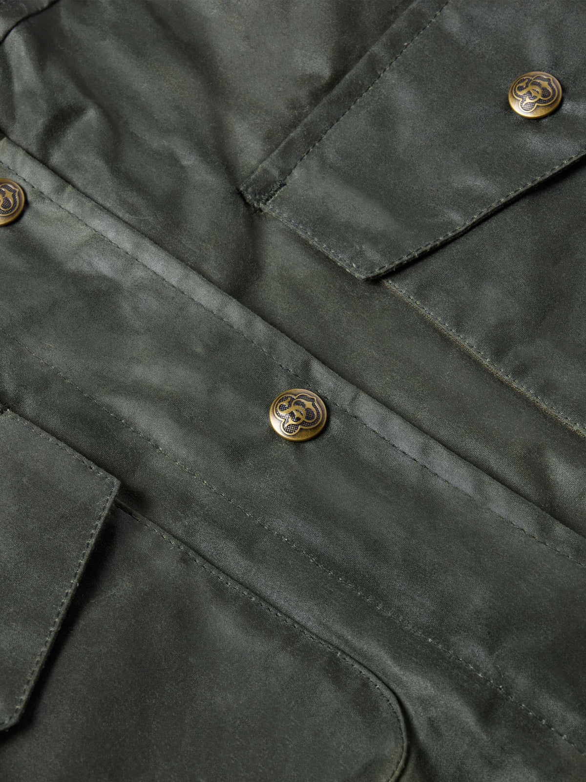 Close-up of dark green waxed barn coat with gold-toned snap buttons and stitched seams.