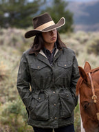 Model in dark green waxed barn coat with brown corduroy collar and chest pocket flaps.