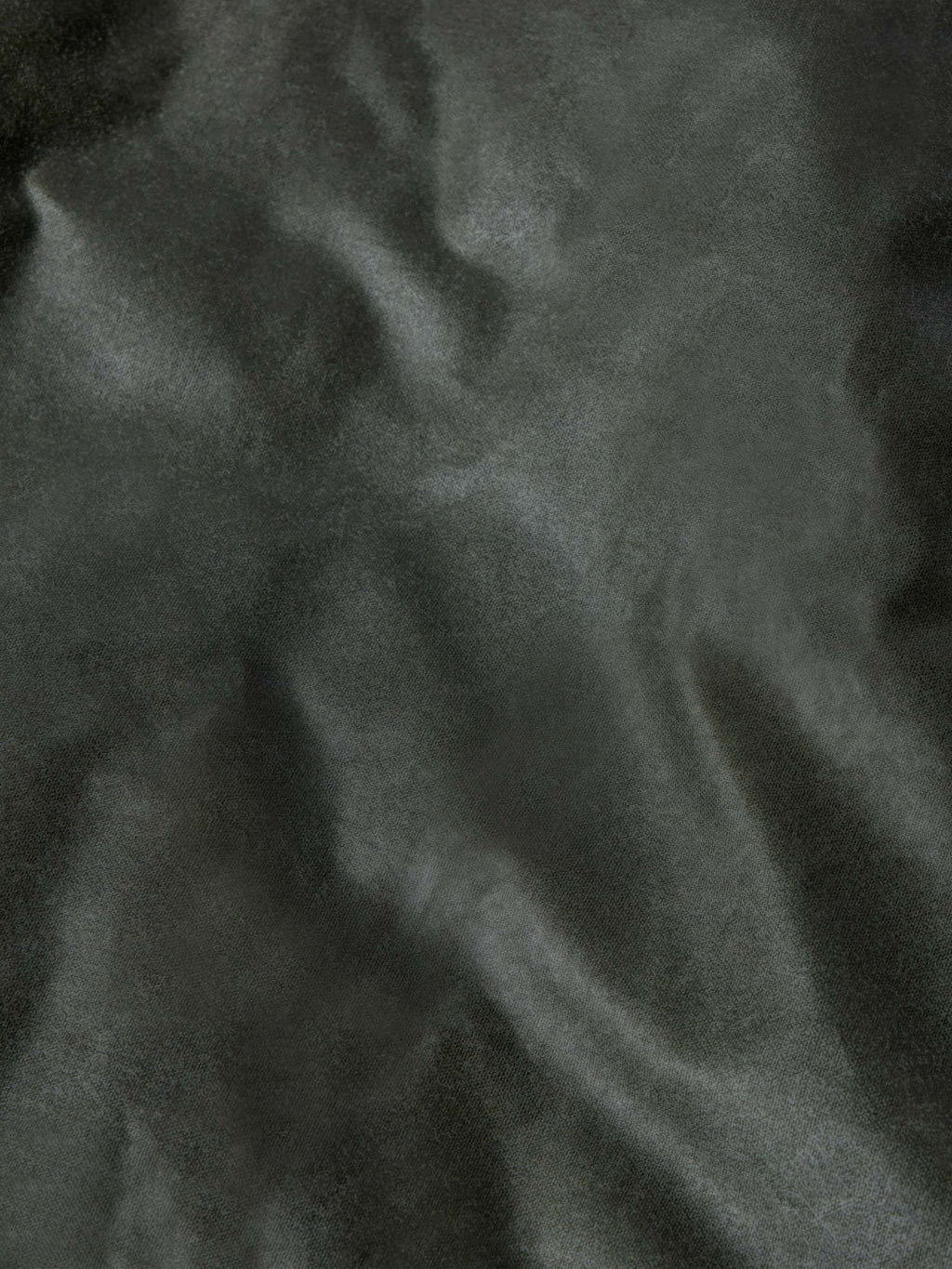 Loden dark green waxed fabric close-up with textured finish and seam lines