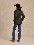 Loden dark green barn coat worn with blue jeans and tan boots, side view