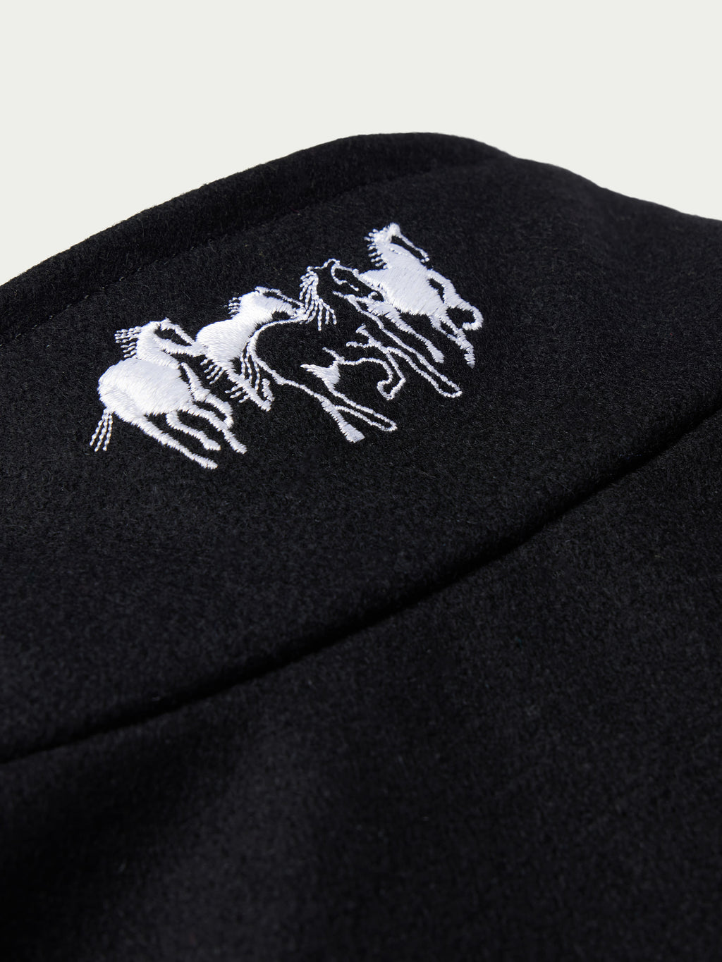 Women's black wool arena jacket sleeve detail with embroidered horse logo