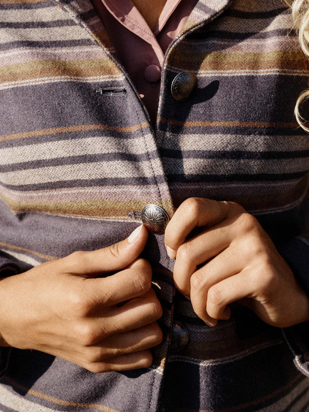 Striped jacket close-up with brown leather collar and snap buttons at placket