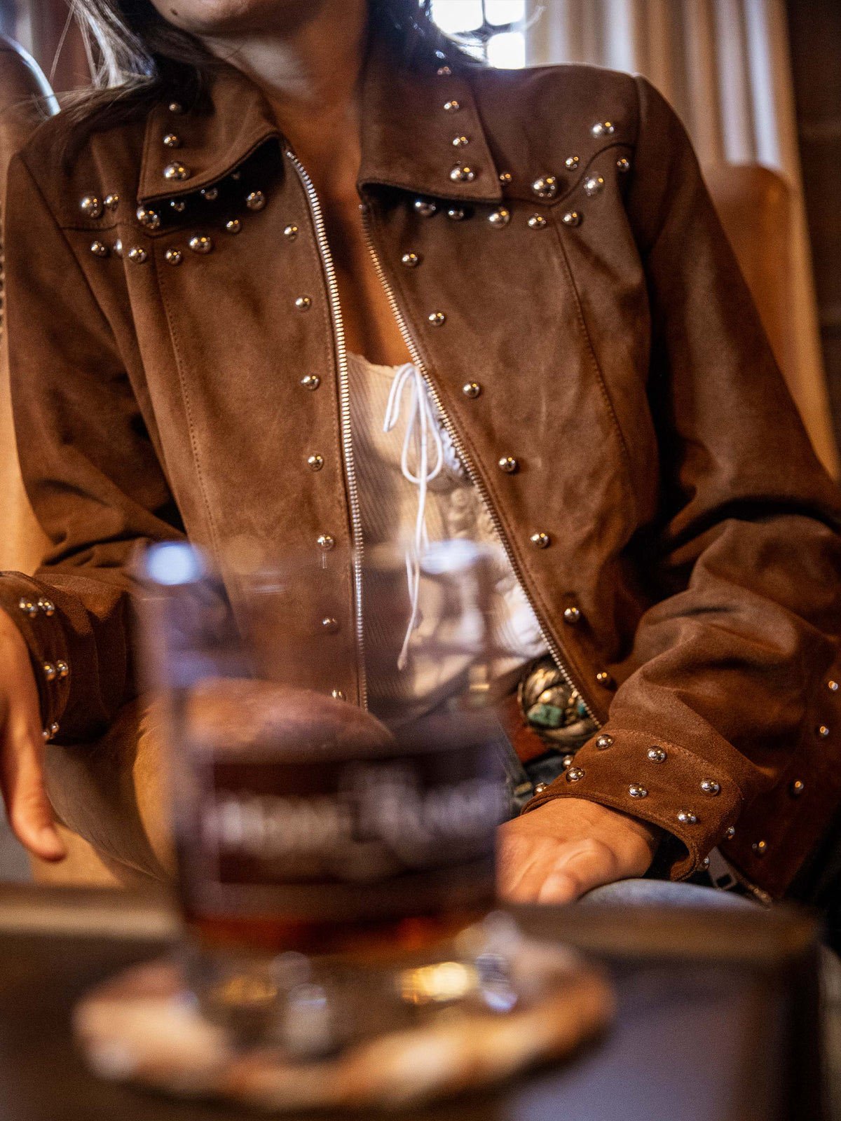 Pecan suede studded jacket on model, front close-up with silver studs and zipper
