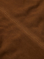 Close-up of pecan brown suede jacket with stitched seam detail along shoulder.