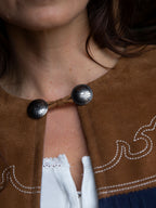 Suede fringe cape neckline with round snap closure and engraved metal buttons