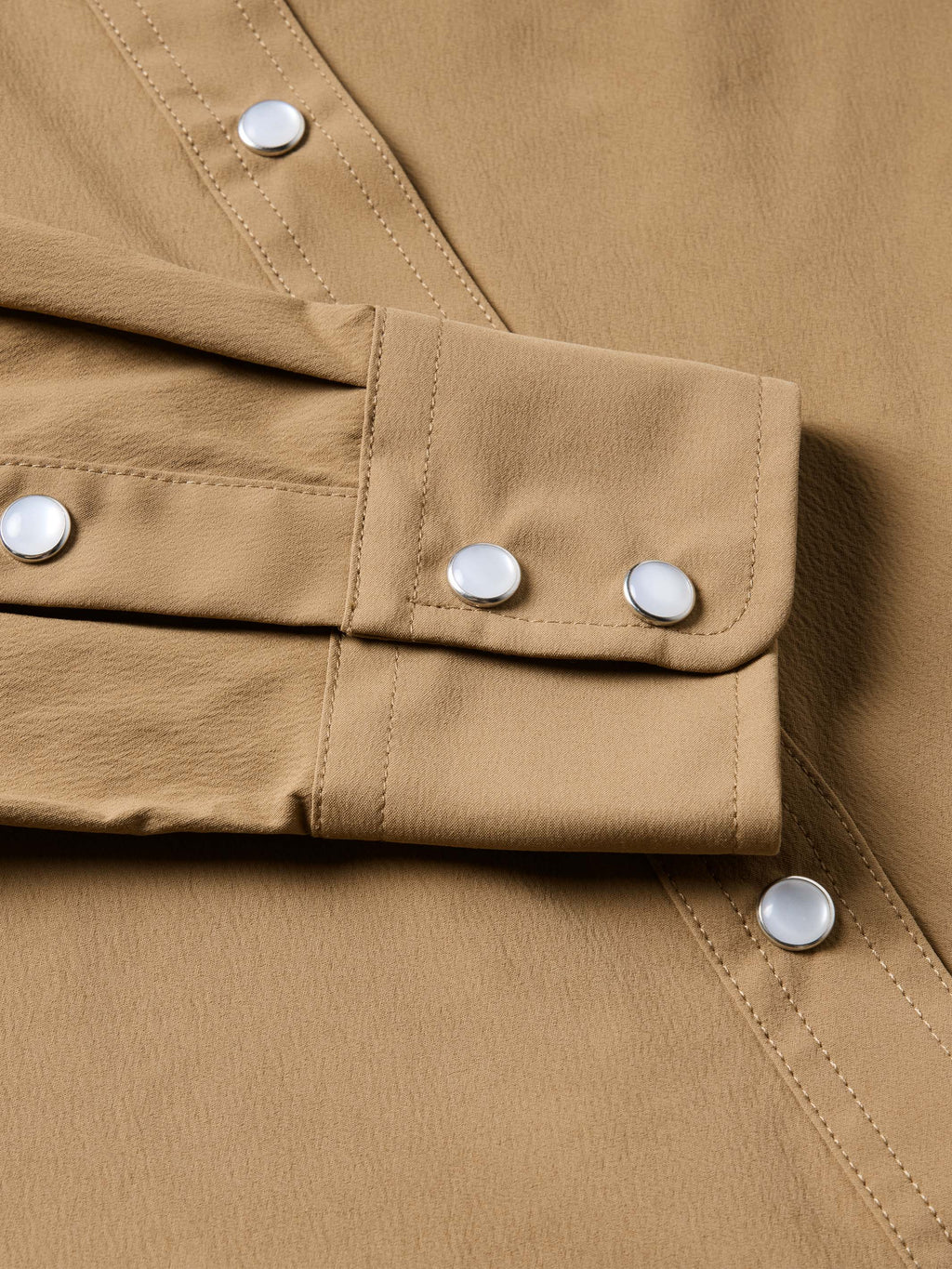 Tan western snap shirt cuff with metal snap buttons and contrast stitching