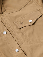 Tan western snap shirt chest pocket with snap closure and embossed decorative logo