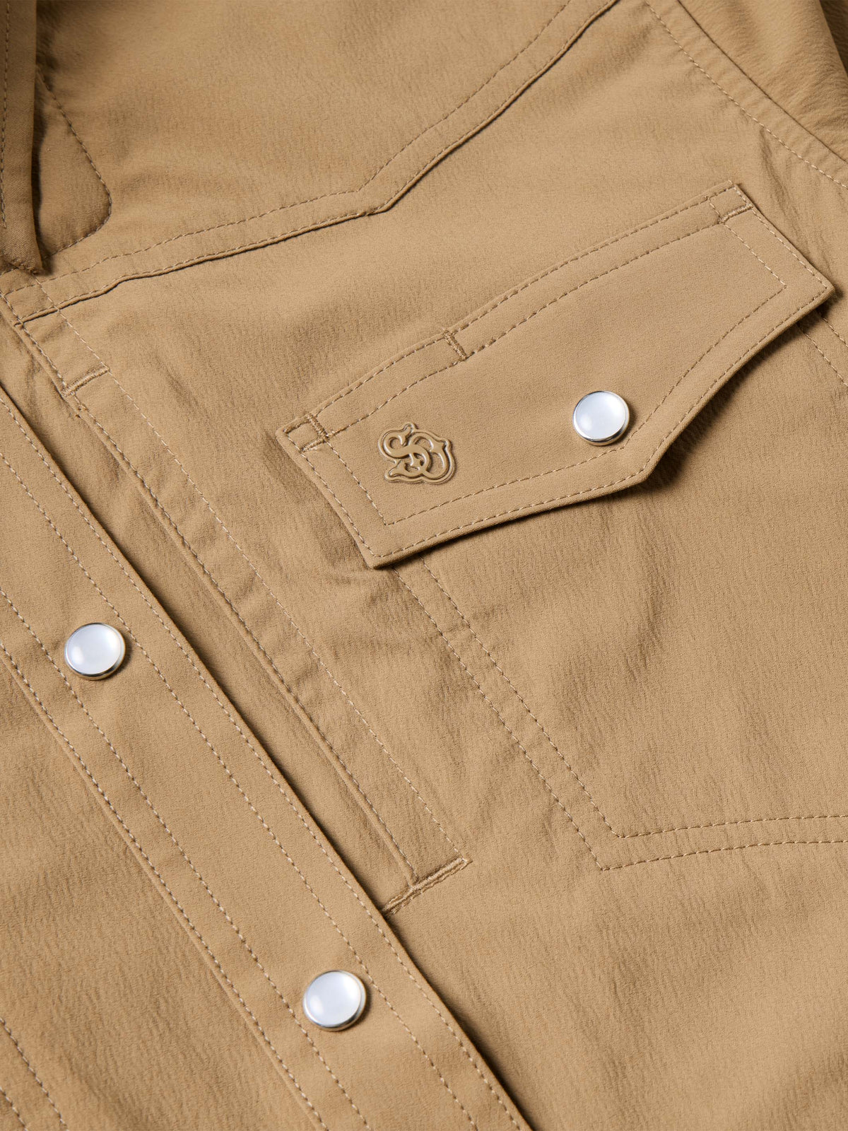 Tan western snap shirt chest pocket with snap closure and embossed decorative logo