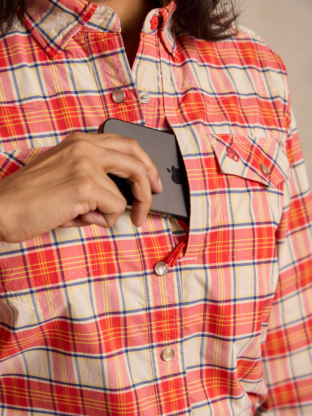 Women’s plaid snap western shirt close-up, red and white snaps on chest placket
