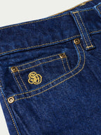 Dark indigo denim jeans close-up of button closure and pocket stitching