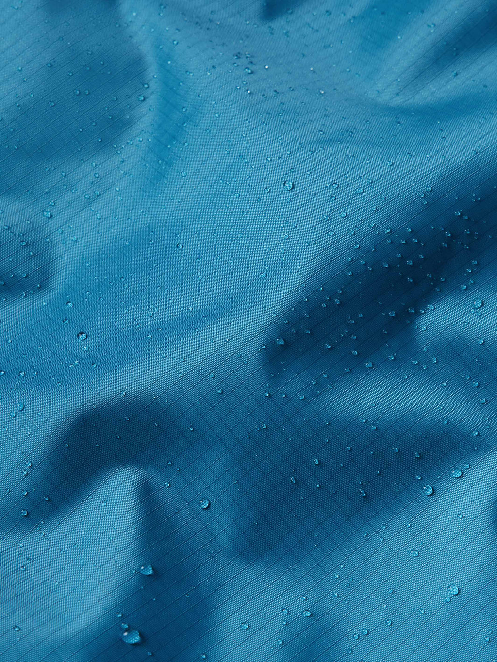Baltic blue rain jacket shell with visible water droplets on fabric