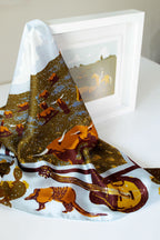 Wild rag scarf draped over frame, gold speckled animal print with dark border.