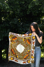 Wild rag scarf held outdoors, gold and orange Western animal map print with border.