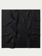 Black jacquard wild rag scarf fabric close-up with ornate swirl pattern
