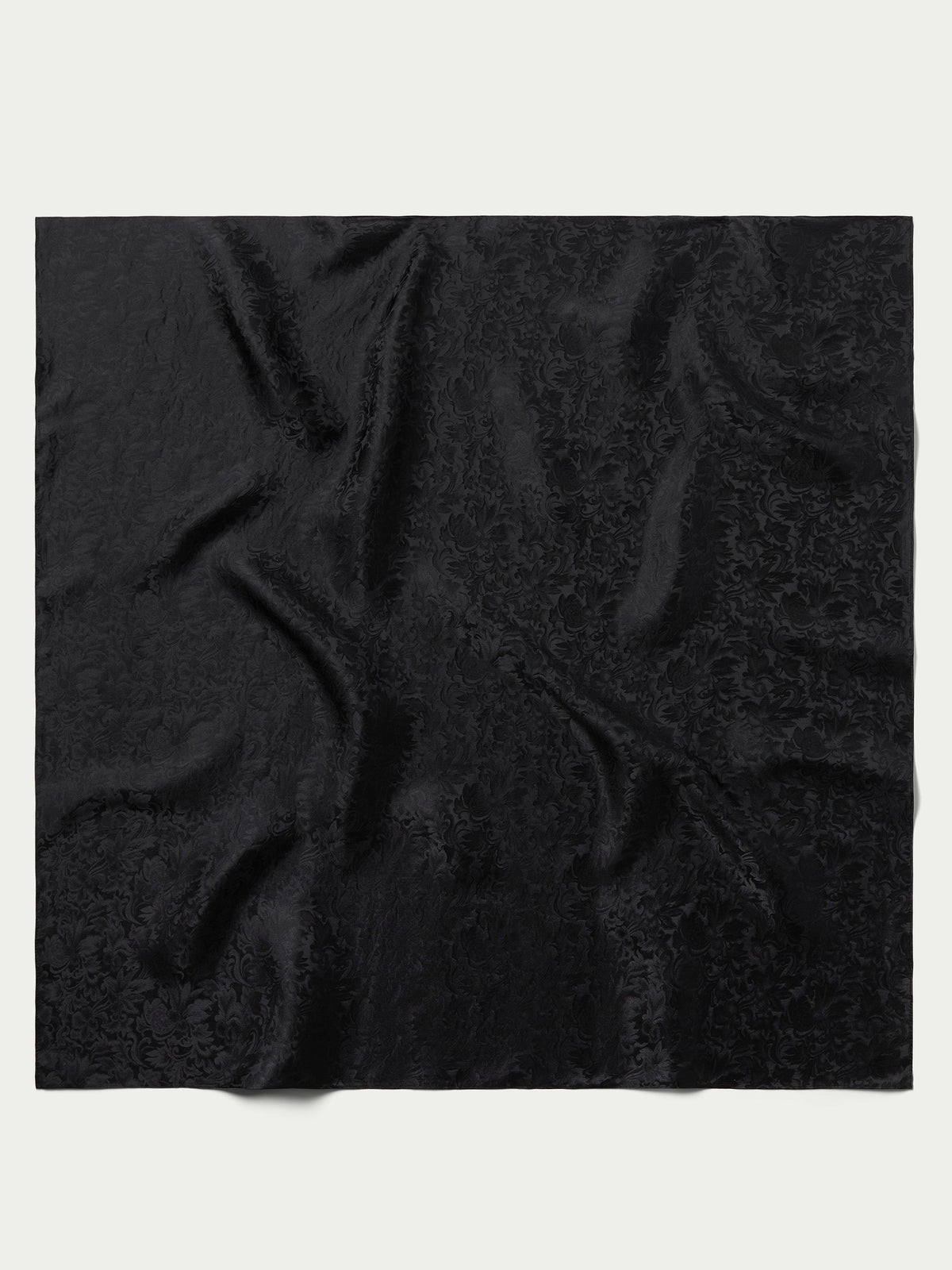 Black jacquard wild rag scarf fabric close-up with ornate swirl pattern