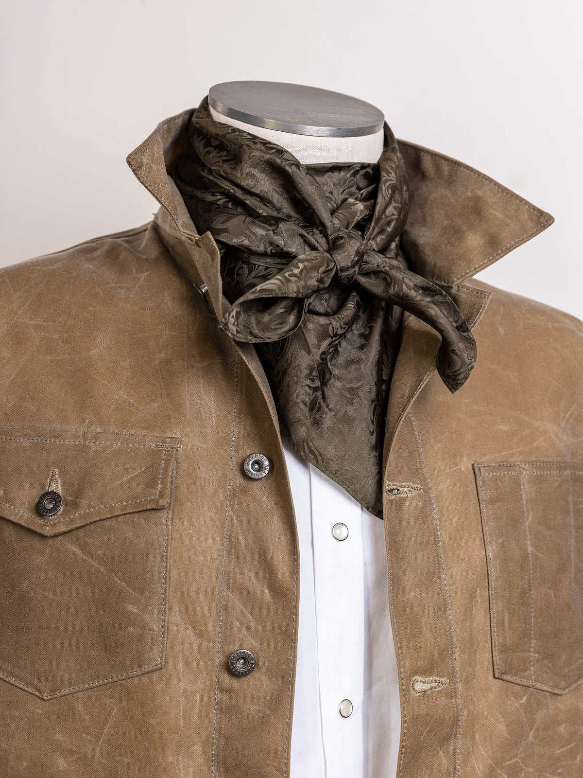 Olive jacquard wild rag with tied bow at front, worn around neck