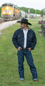 Blue denim dungarees on a man with belt and boots, standing outdoors.