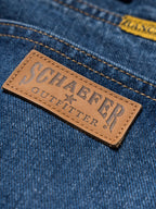 Blue denim dungarees with tan leather brand patch and contrast stitching