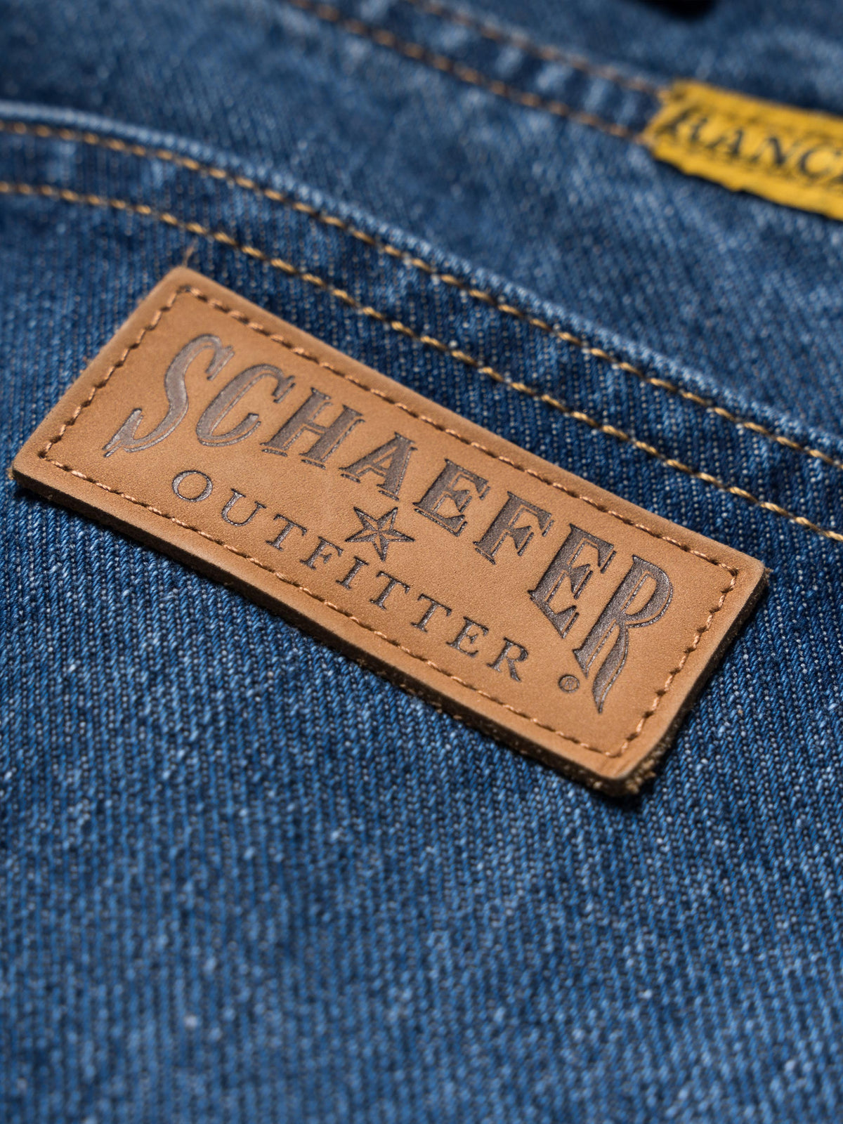 Blue denim dungarees with tan leather brand patch and contrast stitching