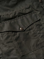 Dark green jacket close-up with button placket and stitched chest pocket flap