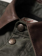 Dark green jacket close-up: brown leather-style collar and engraved snap buttons