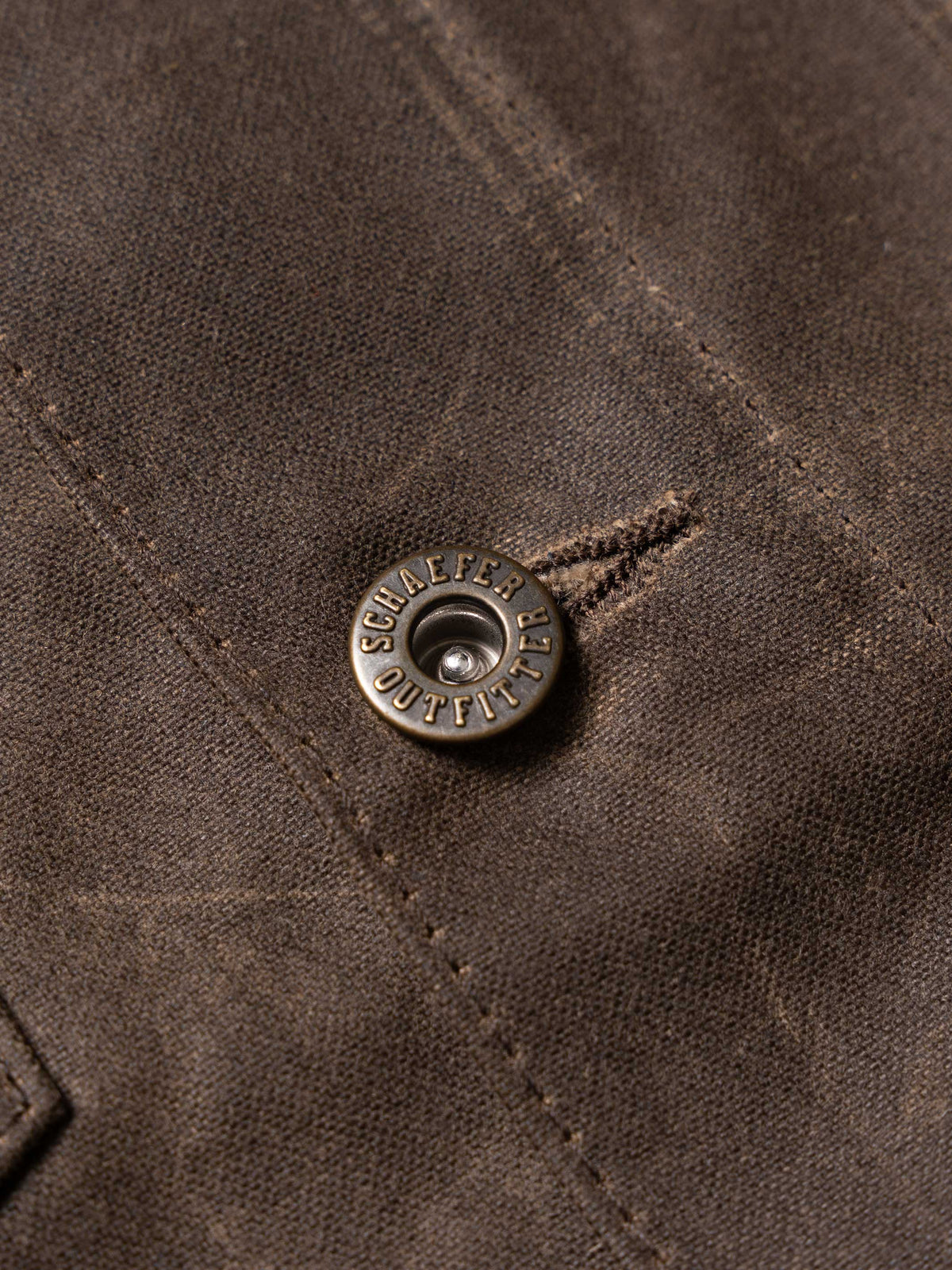 Mesquite brush jacket detail, round branded snap button on dark brown fabric